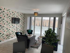 a living room with a couch and a tv and a room with flowers at Exquisite & Contemporary 2 Bed Apartment w Parking 10 mins walk to Papworth, Addenbrookes hospitals & Bio Medical Campus in Trumpington