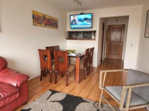 - un salon avec une table, des chaises et une télévision dans l'établissement Avenida del Mar , Primera Linea, edificio Canto del agua, à La Serena