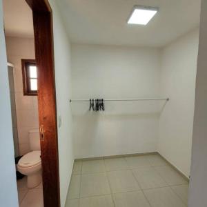 a white bathroom with a toilet and a window at Casa confortável pertinho da praia com garagem e quintal in Rio das Ostras