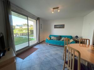 uma sala de estar com um sofá azul e uma mesa em Appartement Jullouville, 2 pièces, 4 personnes - FR-1-361-14 em Jullouville-les-Pins