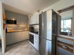 eine Küche mit einem Edelstahlkühlschrank und weißen Schränken in der Unterkunft Appartement à 50m plage avec terrasse et jardin - FR-1-361-14 in Jullouville-les-Pins + 11 Fotos