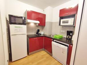 een kleine keuken met rode kasten en een witte koelkast bij L'Eterlou, T3, centre Luchon, wifi, casier à skis, 6 personnes in Luchon