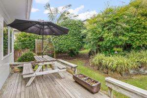 a wooden deck with a picnic table and an umbrella at Gorgeous 2BR Central Akl Retreat - WI-FI - Netflix in Auckland