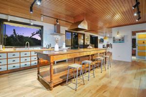 a kitchen with a large wooden island with bar stools at Countryside Calm Getaway with pool and deck in Auckland