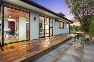 a wooden deck with a dining table on a house at Countryside Calm Getaway with pool and deck in Auckland