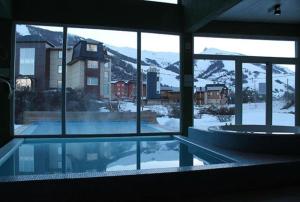 vista para uma piscina através das janelas de um edifício em Dep Catedral em San Carlos de Bariloche