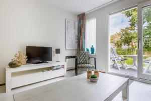 ein Wohnzimmer mit einem TV und einer Glasschiebetür in der Unterkunft Amelander Kaap 109 in Hollum