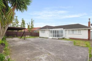 ein weißes Haus mit einer Einfahrt davor in der Unterkunft Homey Hideaway 3 BR w Parking , Wi-fi and Netflix in Auckland