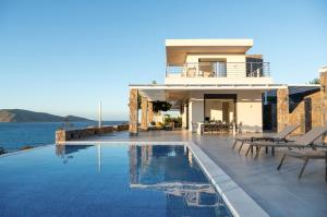 a house with a swimming pool next to the water at Haven Villa in Ierapetra