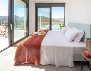 a bedroom with a large white bed and a balcony at Haven Villa in Ierápetra