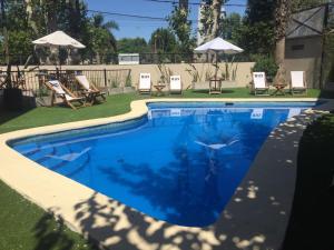 a swimming pool in a yard with chairs and umbrellas at RIO TIGRE HOTEL in Tigre