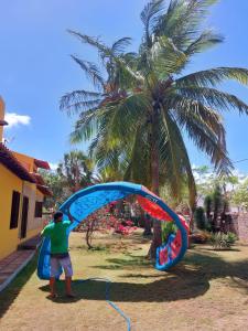 a man holding a kite in front of a palm tree at Quinta Zabelê in Barra Grande