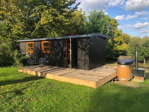 ein schwarzes winziges Haus mit einer Holzterrasse in der Unterkunft Cool de Sources in La Hulpe