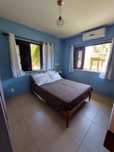a bedroom with a bed with blue walls and windows at Quinta Zabelê in Barra Grande