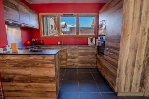 a kitchen with red walls and wooden cabinets at Chalet de l'Olympe A2 in Les Allues +20 photos