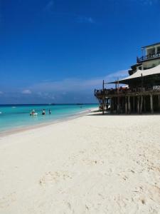 a beach with a pier and people in the water at Savi House Nungwi in Nungwi