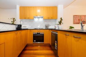 a kitchen with wooden cabinets and a stove top oven at Brunswick 3bdrm townhouse, with parking by Custom Bnb Hosting in Melbourne