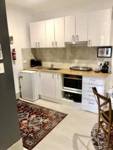 a kitchen with white cabinets and a stove top oven at Contemporary Studio in the heart of Paddington in Brisbane