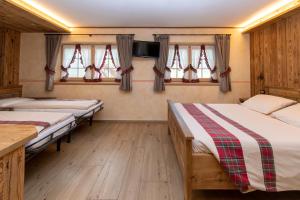 dwa łóżka w pokoju z oknami i telewizorem w obiekcie Al Solìf w Livigno