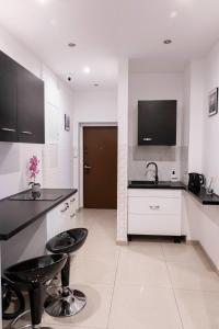 a white kitchen with black counter tops and stools at ClickTheFlat Royal Route Warecka Apart Rooms in Warsaw