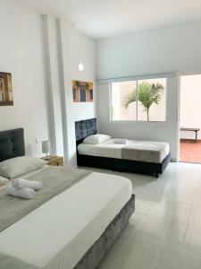 a bedroom with two beds and a large window at Hotel Santorini in San Gil