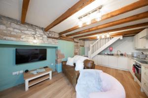 ein Wohnzimmer mit Sofa und Fernseher in der Unterkunft Ollerenshaw Cottage in Buxton