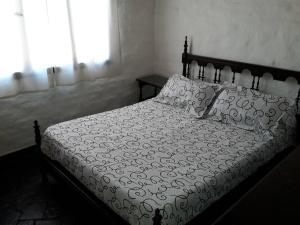 1 cama con edredón y almohadas blancos en Alquilo Casa en Tanti in 