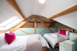 Zimmer im Dachgeschoss mit 2 Betten und rosa Kissen in der Unterkunft Nadin Cottage in Buxton