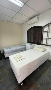 1 dormitorio con 2 camas y nevera en Suítes Nosso Lar, en Río de Janeiro