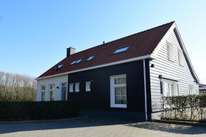 una casa en blanco y negro con techo en Woning zeldenrust 4, en Oostkapelle