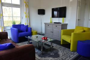 een woonkamer met kleurrijke stoelen en een televisie bij Woning zeldenrust 4 in Oostkapelle