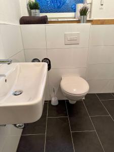 a bathroom with a white sink and a toilet at bee Apartment: Ideal für Gruppen & Monteure in Lahnau