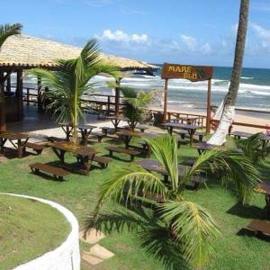 uma praia com muitas mesas de piquenique e o oceano em Pousada Familiar e Domiciliar - Perto do Aeroporto de Salvador em Lauro de Freitas