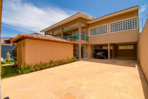 a house with a car parked in the driveway at Casa Pouso das Fadas com Arrumadeira e Cozinheira Profissional in Maragogi