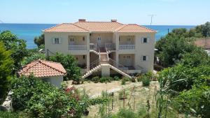 a large house with a staircase in front of the ocean at Akti Zaga Apartments in Koroni