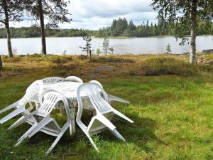 duas cadeiras e uma mesa na relva perto de um lago em 5 person holiday home in L GDE em Himmersundet