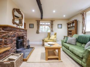 a living room with a green couch and a fireplace at Posbury Lodge in Crediton