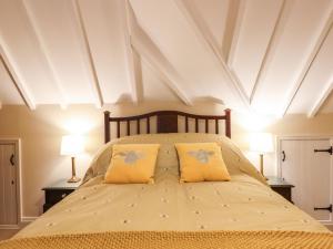 a bedroom with a large bed with two yellow pillows at Posbury Lodge in Crediton