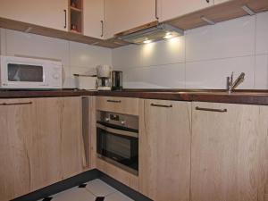 a kitchen with wooden cabinets and a microwave at Gemütliche Ferienwohnung auf Fehmarn in Petersdorf auf Fehmarn