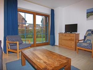a living room with a tv and a table and chairs at Gemütliche Ferienwohnung auf Fehmarn in Petersdorf auf Fehmarn
