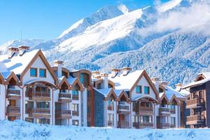 a hotel with snow covered mountains in the background at Secluded Mountain Cozy Studio with Fireplace in Bansko