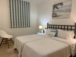 una camera da letto con un letto con lenzuola bianche e una sedia di Espectacular casa en la playa a Fuengirola