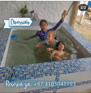 una donna e due bambini in piscina di Cabañas camino al cielo a Fúquene