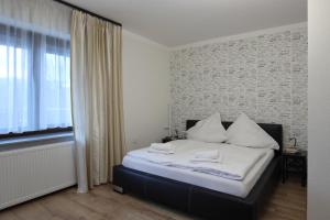 a bedroom with a bed with white sheets and a window at Willa na Plażowej in Węgierska Górka