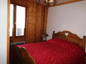 1 dormitorio con cama de madera y colcha roja en Chalet Aussois, 6 pièces, 14 personnes - FR-1-508-28, en Aussois