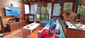 ein Wohnzimmer mit einem Sofa und einem TV in der Unterkunft Casa Serrana, 4 quartos com ar e piscina aquecida em meio à Natureza de Itaipava in Itaipava