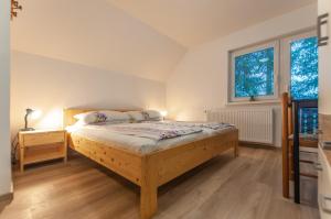 a bedroom with a wooden bed and two windows at Apartment Ticar in Bohinj