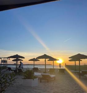 a beach with chairs and umbrellas and the sunset at Aparthotel Por do Sol in Sal Rei