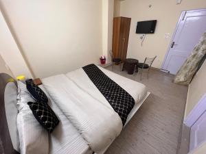 a bedroom with a bed with white sheets and black pillows at Wonder View in Shimla