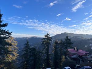 a view of a mountain with trees and a house at Wonder View in Shimla